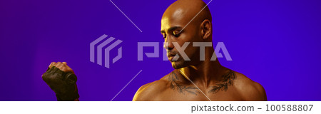 Sporty man performs exercises with expander on studio background. Strength and motivation 100588807