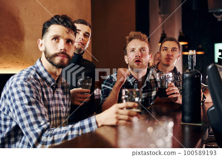 Expressive people watching soccer. Group of people together indoors in the pub have fun at weekend time 100589193