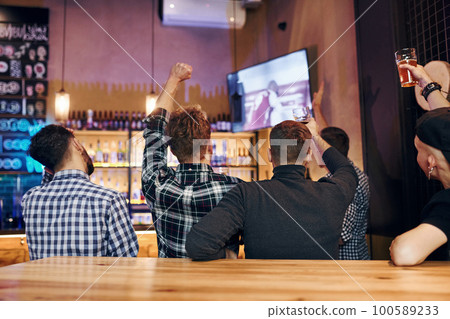Football fans watching TV. Group of people together indoors in the pub have fun at weekend time 100589233