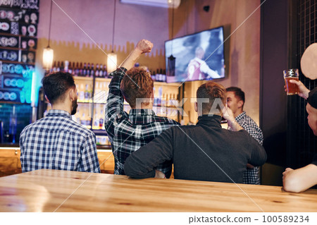 Football fans watching TV. Group of people together indoors in the pub have fun at weekend time 100589234