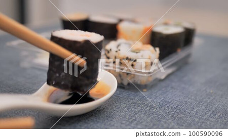 take a roll with chopsticks and dip it in soy sauce take a roll with chopsticks and dip it in soy sauce 100590096