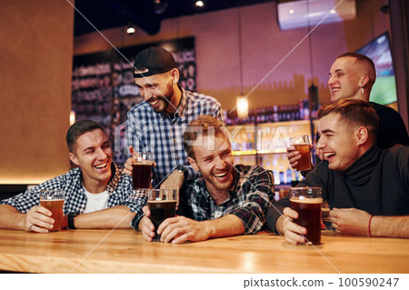 Football fans watching TV. Group of people together indoors in the pub have fun at weekend time Football fans watching TV. Group of people together indoors in the pub have fun at weekend time 100590247