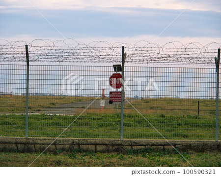 Airport security perimeter fencing system with razor wire with SRA security restricted area stop sign and airplanes behind Airport security perimeter fencing system with razor wire with SRA security restricted area stop sign and airplanes behind 100590321