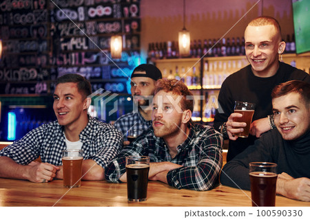 Soccer fans celebrating victory. Group of people together indoors in the pub have fun at weekend time 100590330