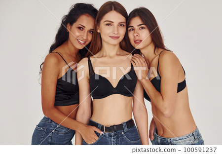 Embracing each other. Three young women in lingerie together indoors. White background 100591237
