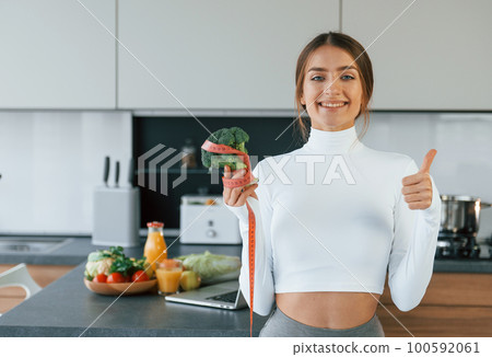 Young european woman is indoors at kitchen indoors with healthy food 100592061