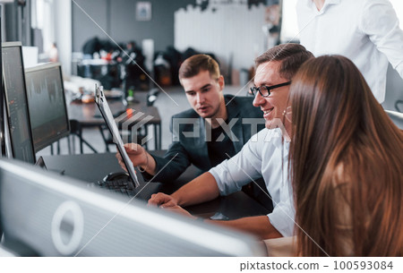 Holds document in hands. Team of stockbrokers works in modern office with many display screens Holds document in hands. Team of stockbrokers works in modern office with many display screens 100593084