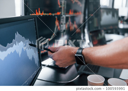 Close up view of man's hand that points at part of stock graph on display Close up view of man's hand that points at part of stock graph on display 100593991