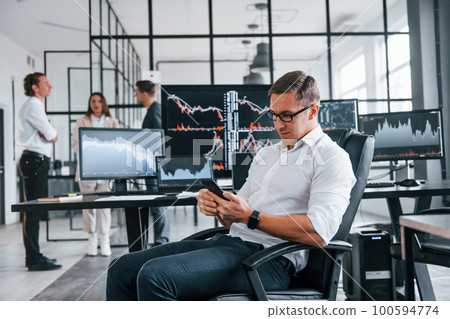 Ordinary office day. Team of stockbrokers works in indoors with many display screens Ordinary office day. Team of stockbrokers works in indoors with many display screens 100594774