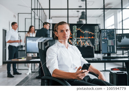 Ordinary office day. Team of stockbrokers works in indoors with many display screens 100594779