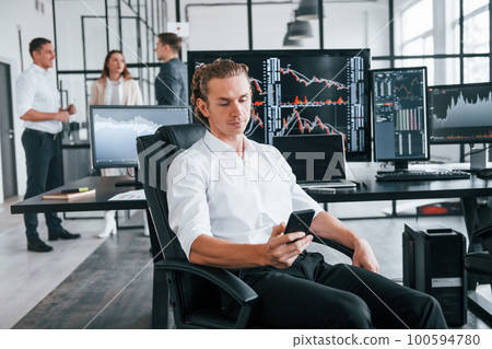 Ordinary office day. Team of stockbrokers works in indoors with many display screens Ordinary office day. Team of stockbrokers works in indoors with many display screens 100594780