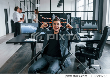 Ordinary office day. Team of stockbrokers works in indoors with many display screens Ordinary office day. Team of stockbrokers works in indoors with many display screens 100594788