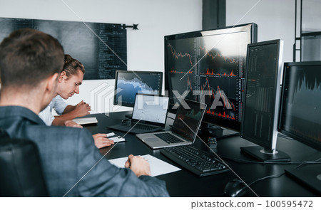 Conception of teamwork. Team of stockbrokers works in modern office with many display screens 100595472