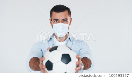 Football fan with soccer ball. Young handsome man standing indoors against white background 100595537