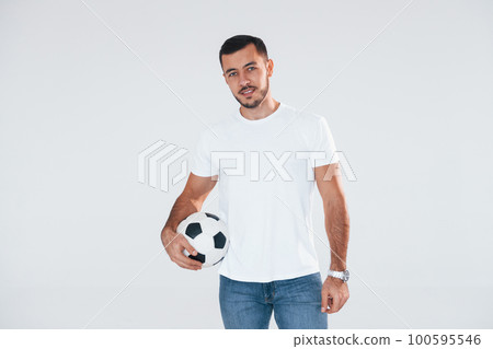 Football fan with soccer ball. Young handsome man standing indoors against white background Football fan with soccer ball. Young handsome man standing indoors against white background 100595546