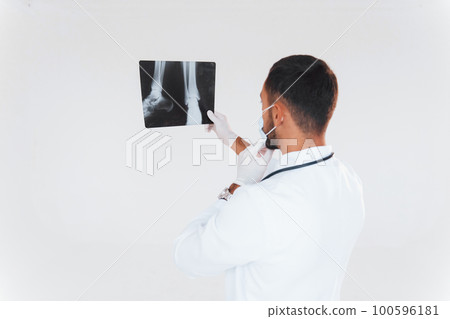 Medic with x-ray. Young handsome man standing indoors against white background Medic with x-ray. Young handsome man standing indoors against white background 100596181