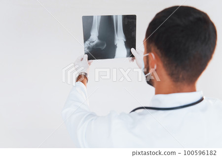 Medic with x-ray. Young handsome man standing indoors against white background 100596182