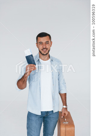 Tourist with ticket. Young handsome man standing indoors against white background 100596319