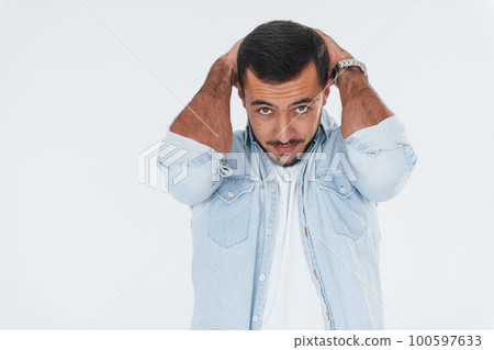 Stressful young man standing indoors against white background 100597633