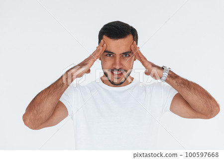 Feels headache. Young handsome man standing indoors against white background 100597668