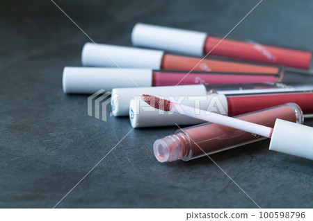 Liquid lipstick or lip gloss with open tube on stone background 100598796