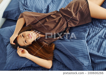 Young woman lying down and resting. Interior and design of beautiful modern bedroom at daytime Young woman lying down and resting. Interior and design of beautiful modern bedroom at daytime 100600266
