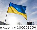 Flag with yellow and blue striped colors of Ukraine waving in the wind with a blue sky and sun. 100602230