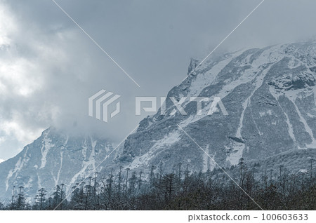 Winter Cloudy Foggy Mountain Landscape. Snow-covered mountain covered with floating rainy clouds. Winter Cloudy Foggy Mountain Landscape. Snow-covered mountain covered with floating rainy clouds. 100603633