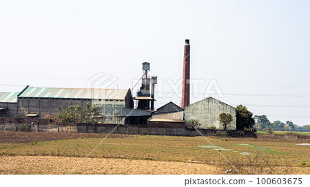 Industrial Factory Building landscape against clear sky background and agriculture field in the foreground. 100603675