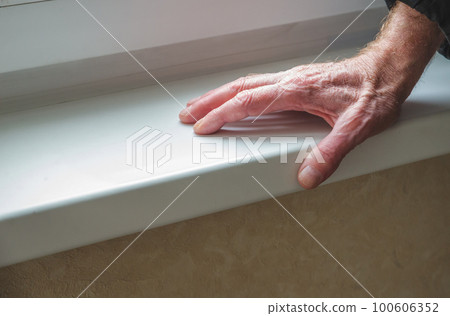 Senior man's wrinkled hand near the window. Senior man's wrinkled hand near the window. 100606352