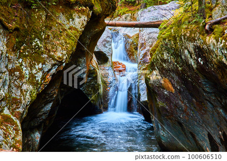 Narrow gorge eye level to waterfall raging down with mossy rocks 100606510