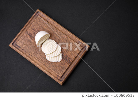 Delicious fresh mozzarella cut into slices on a wooden cutting board Delicious fresh mozzarella cut into slices on a wooden cutting board 100609532