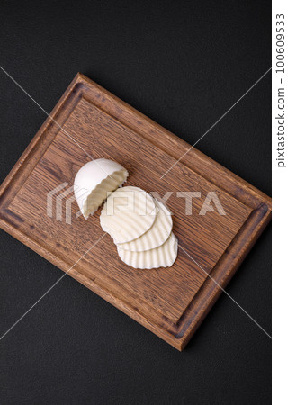 Delicious fresh mozzarella cut into slices on a wooden cutting board Delicious fresh mozzarella cut into slices on a wooden cutting board 100609533