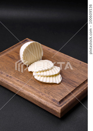 Delicious fresh mozzarella cut into slices on a wooden cutting board Delicious fresh mozzarella cut into slices on a wooden cutting board 100609536