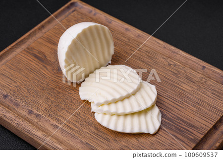 Delicious fresh mozzarella cut into slices on a wooden cutting board Delicious fresh mozzarella cut into slices on a wooden cutting board 100609537
