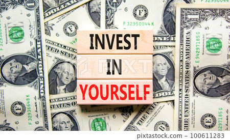 Invest in yourself symbol. Concept words Invest in yourself on wooden block on a beautiful background from dollar bills. Dollar bills. Business and Invest in yourself concept. Copy space. 100611283