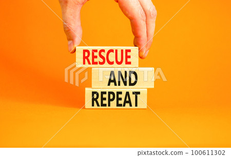 Rescue and repeat symbol. Concept words Rescue and repeat on wooden block on a beautiful orange table orange background. Businessman hand. Business rescue and repeat concept. Copy space. 100611302