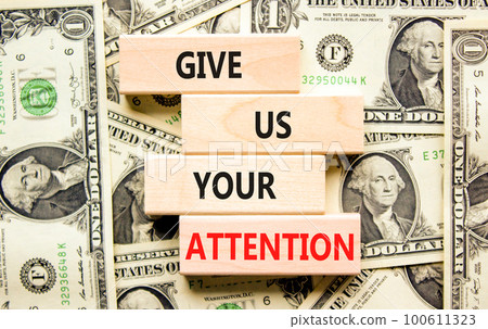 Give us your attention symbol. Concept words Give us your attention on wooden block. Beautiful background from dollar bills. Motivational business give us your attention concept. Copy space. 100611323
