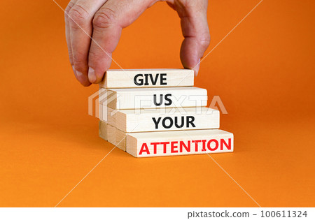 Give us your attention symbol. Concept words Give us your attention on wooden block. Beautiful orange table orange background. Motivational business give us your attention concept. Copy space. 100611324
