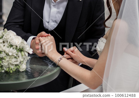 a man and a woman hold hands at the wedding of newlyweds a man and a woman hold hands at the wedding of newlyweds 100612488