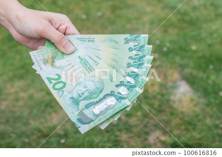 Cropped shot view of someone showing the money (New Zealand 20$ dollars).  New Zealand dollar is the official currency of New Zealand since 1967. 100616816