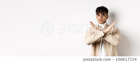 Image of serious young guy in glasses say no, showing cross gesture, make stop sign to disagree or prohibit something, standing on white background Image of serious young guy in glasses say no, showing cross gesture, make stop sign to disagree or prohibit something, standing on white background 100617154