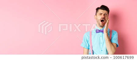 Image of tired guy in bow-tie yawning with opened mouth and closed eyes, standing sleepy, feeling fatigue, standing over pink background 100617699