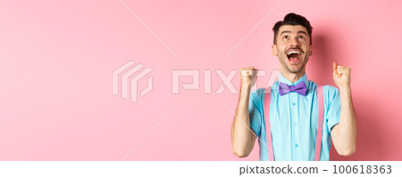 Relieved and happy man thanking god, looking up in sky while celebrating victory, winning prize and cheering, triumphing over pink background Relieved and happy man thanking god, looking up in sky while celebrating victory, winning prize and cheering, triumphing over pink background 100618363
