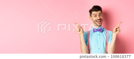 Handsome funny guy pointing fingers aside, showing left and right logo and smiling, recommending two choices, standing on pink background Handsome funny guy pointing fingers aside, showing left and right logo and smiling, recommending two choices, standing on pink background 100618377