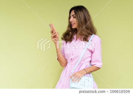 Young woman in casual wear isolated on green background looking at phone screen with big smile reading message Young woman in casual wear isolated on green background looking at phone screen with big smile reading message 100618509