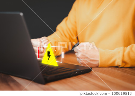 Young man is angry and frustrated when he learns that his the laptop computer's battery is dead and did not bring the charger adapter. No power battery. 100619813