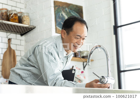 一個穿著工作服的男人站在廚房裡 100621017