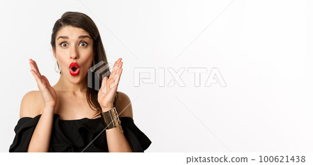 Fashion and beauty concept. Close-up of excited woman with makeup and red lipstick on, looking surprised and glad, standing over white background Fashion and beauty concept. Close-up of excited woman with makeup and red lipstick on, looking surprised and glad, standing over white background 100621438