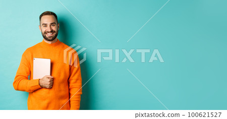 Handsome freelancer man holding laptop and smiling, standing happy over light blue background 100621527